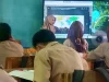 Siswa SMP menyimak guru mengajar di depan layar di sebuah ruang kelas