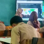 Siswa SMP menyimak guru mengajar di depan layar di sebuah ruang kelas