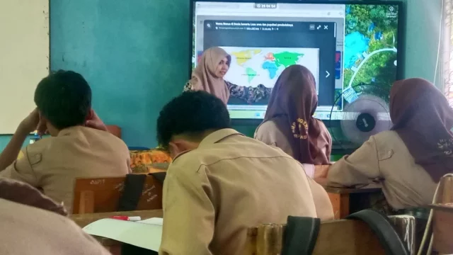 Siswa SMP menyimak guru mengajar di depan layar di sebuah ruang kelas