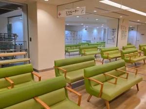 Ruang tunggu rumah sakit yang lengang dengan deretan sofa hijau di Shibuya, Tokyo