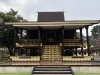 Rumah Adat Banjar bergaya Bubungan Tinggi dengan tangga berukir emas.