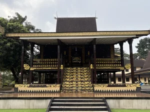 Rumah Adat Banjar bergaya Bubungan Tinggi dengan tangga berukir emas.