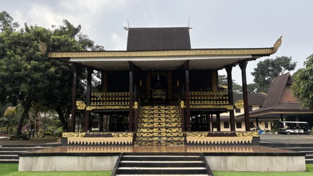 Rumah Adat Banjar bergaya Bubungan Tinggi dengan tangga berukir emas.
