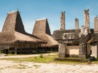 Rumah adat beratap menjulang dan kubur batu megalitik berukir di Kampung Rende, Sumba Timur