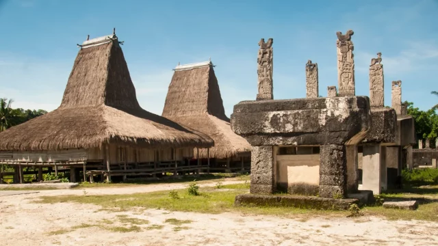 Rumah adat beratap menjulang dan kubur batu megalitik berukir di Kampung Rende, Sumba Timur