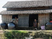 Rumah bambu beratap rumbia dengan tempayan air di tepi sungai, Pyapon, Delta Ayeyarwady, Myanmar
