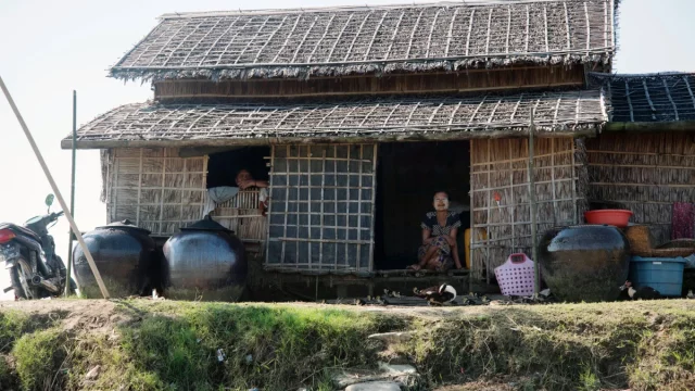 Rumah bambu beratap rumbia dengan tempayan air di tepi sungai, Pyapon, Delta Ayeyarwady, Myanmar