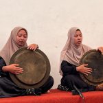 Dua pesalawat perempuan memangku dulang kuningan dalam pertunjukan salawat dulang.