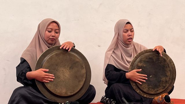 Dua pesalawat perempuan memangku dulang kuningan dalam pertunjukan salawat dulang.