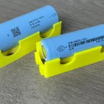 Dua sel baterai litium ion silinder tipe 18650 dan 21700 di atas dudukan