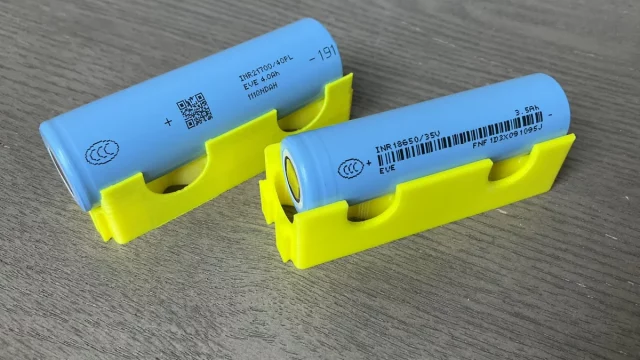 Dua sel baterai litium ion silinder tipe 18650 dan 21700 di atas dudukan