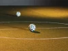 Bola futsal tergeletak di lapangan dalam ruangan bercahaya temaram