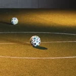 Bola futsal tergeletak di lapangan dalam ruangan bercahaya temaram