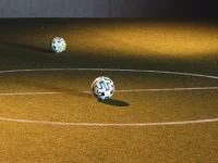 Bola futsal tergeletak di lapangan dalam ruangan bercahaya temaram