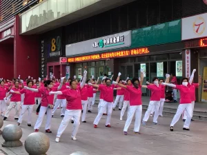 Puluhan perempuan paruh baya berkaus merah muda menari senam bersama di Shenyang, Tiongkok