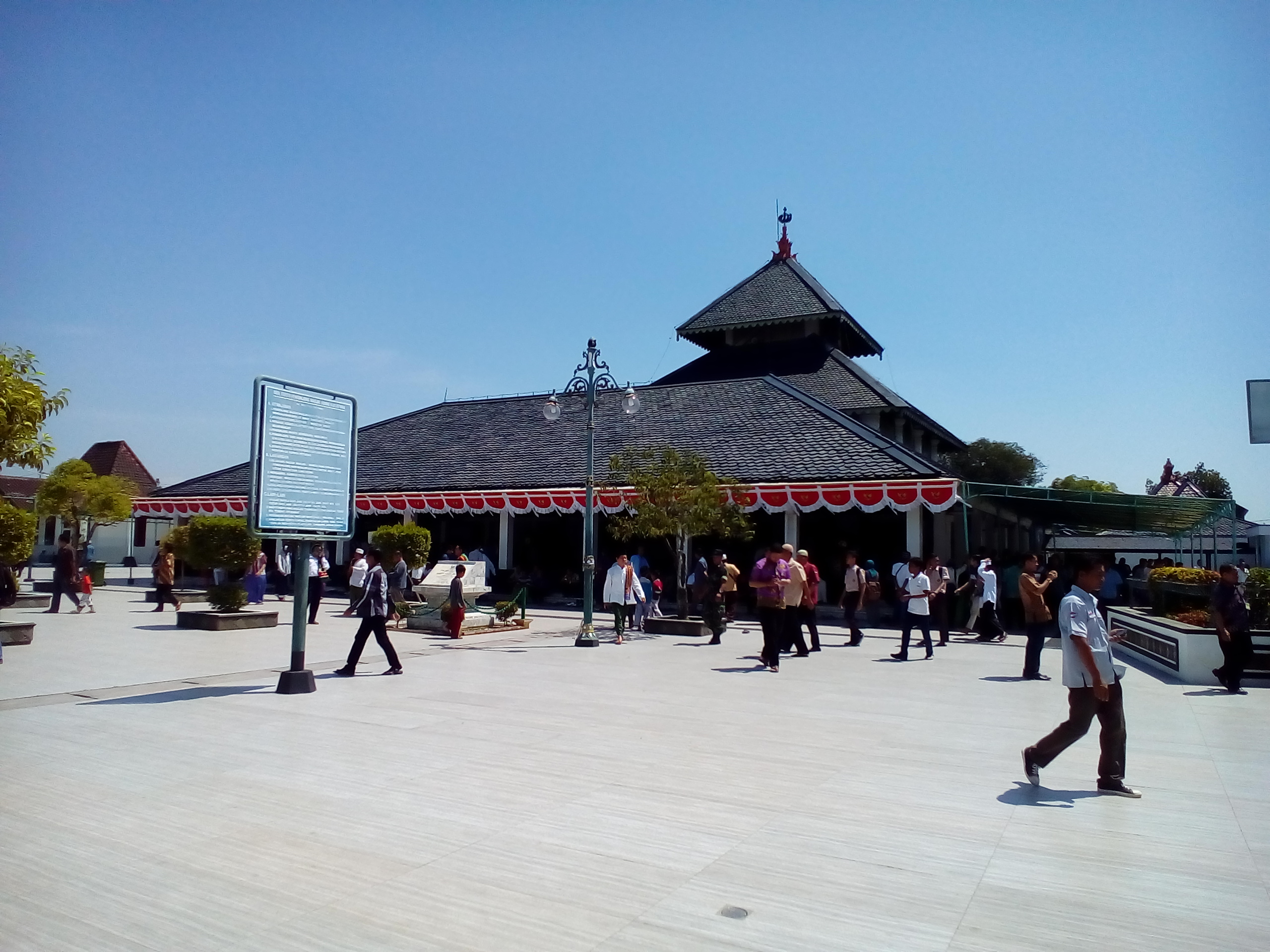 Masjid Agung Demak beratap tumpang tiga dengan halaman yang ramai pengunjung.