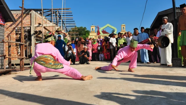 Dua pesilat berbaju merah muda beradu silat dalam penyambutan pengantin adat Melayu