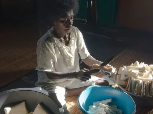 Seorang perempuan memotong sagu kering menjadi balok di samping baskom biru