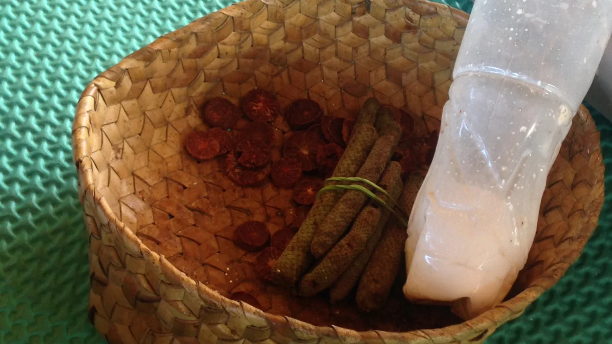Pinang iris dan sirih buah dalam wadah anyaman di samping botol kapur