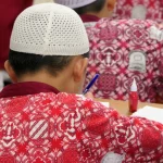 Siswa sekolah dasar berseragam batik mengerjakan soal ujian di Jambi