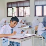 Ilustrasi murid-murid duduk di bangku kelas mengerjakan tugas tulis.