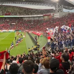 Tribun stadion dipenuhi suporter yang mengibarkan bendera saat pertandingan