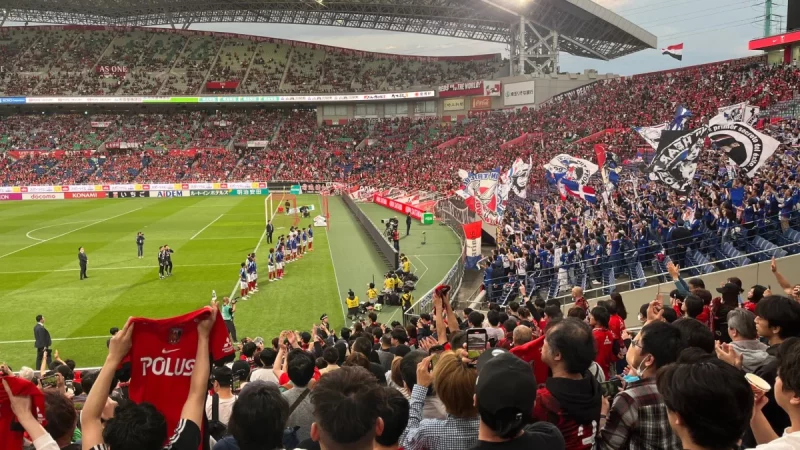Tribun stadion dipenuhi suporter yang mengibarkan bendera saat pertandingan