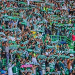 Kerumunan suporter sepak bola mengibarkan syal di tribun stadion