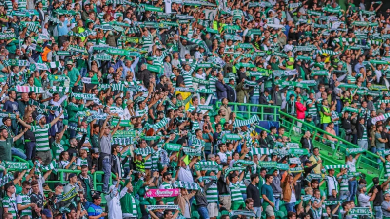 Kerumunan suporter sepak bola mengibarkan syal di tribun stadion