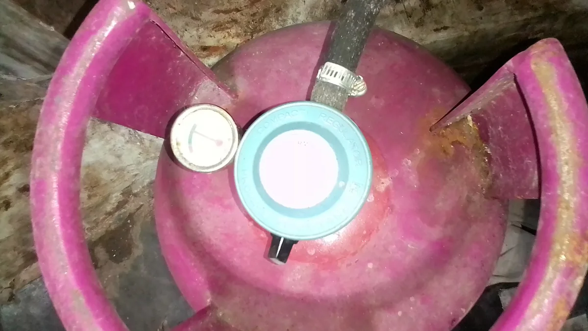 Tabung gas LPG dengan regulator dan selang terpasang, dilihat dari atas
