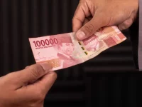Ilustrasi dua tangan bertukar selembar uang Rp100.000