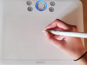 Tangan menggambar menggunakan pena digital di atas tablet grafis.