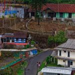 Ilustrasi jalan kampung dengan rumah-rumah warga di kiri dan kanan.