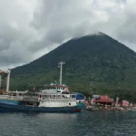 Kapal bersandar di Teluk Jailolo, Halmahera Barat, dengan gunung berselimut awan