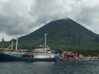 Kapal bersandar di Teluk Jailolo, Halmahera Barat, dengan gunung berselimut awan