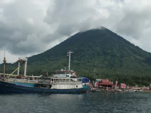 Kapal bersandar di Teluk Jailolo, Halmahera Barat, dengan gunung berselimut awan
