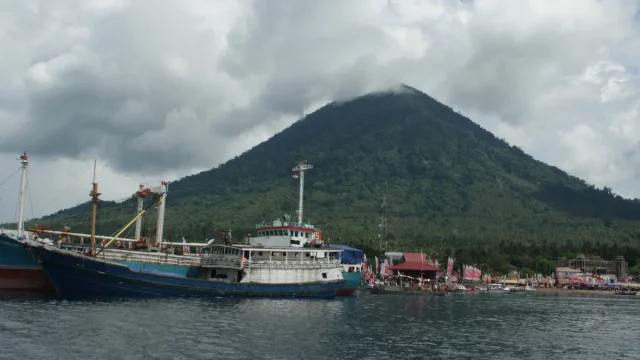 Kapal bersandar di Teluk Jailolo, Halmahera Barat, dengan gunung berselimut awan