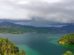 Teluk Tomori berair hijau toska dengan bukit berhutan dan permukiman tepi teluk, Morowali Utara