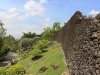 Tembok batu karang Benteng Keraton Buton menjulang di samping jalan setapak, Kota Baubau