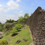 Tembok batu karang Benteng Keraton Buton menjulang di samping jalan setapak, Kota Baubau