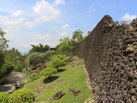 Tembok batu karang Benteng Keraton Buton menjulang di samping jalan setapak, Kota Baubau