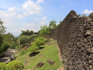 Tembok batu karang Benteng Keraton Buton menjulang di samping jalan setapak, Kota Baubau