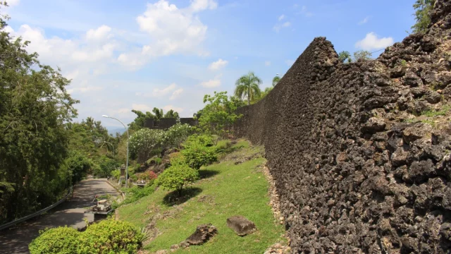 Tembok batu karang Benteng Keraton Buton menjulang di samping jalan setapak, Kota Baubau