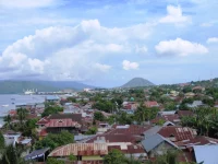 Atap-atap rumah Kota Ternate dengan teluk dan gunung di kejauhan