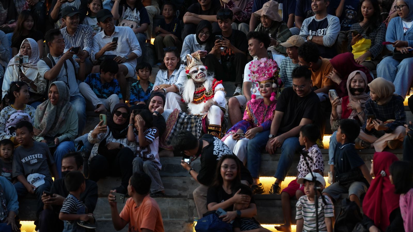 Kesurupan Gen Z di Terbang Buhun Majalaya 2 Ilustrasi kerumunan penonton duduk berdesakan menyaksikan sebuah pertunjukan, sebagian merekam dengan telepon genggam.