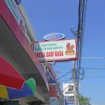 Papan nama pusat oleh-oleh khas Lampung Aneka Sari Rasa di bawah langit biru