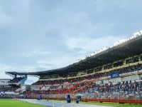 Tribune stadion penuh penonton di bawah lampu sorot