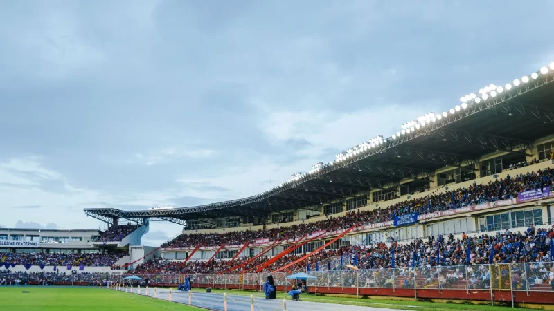 Tribune stadion penuh penonton di bawah lampu sorot