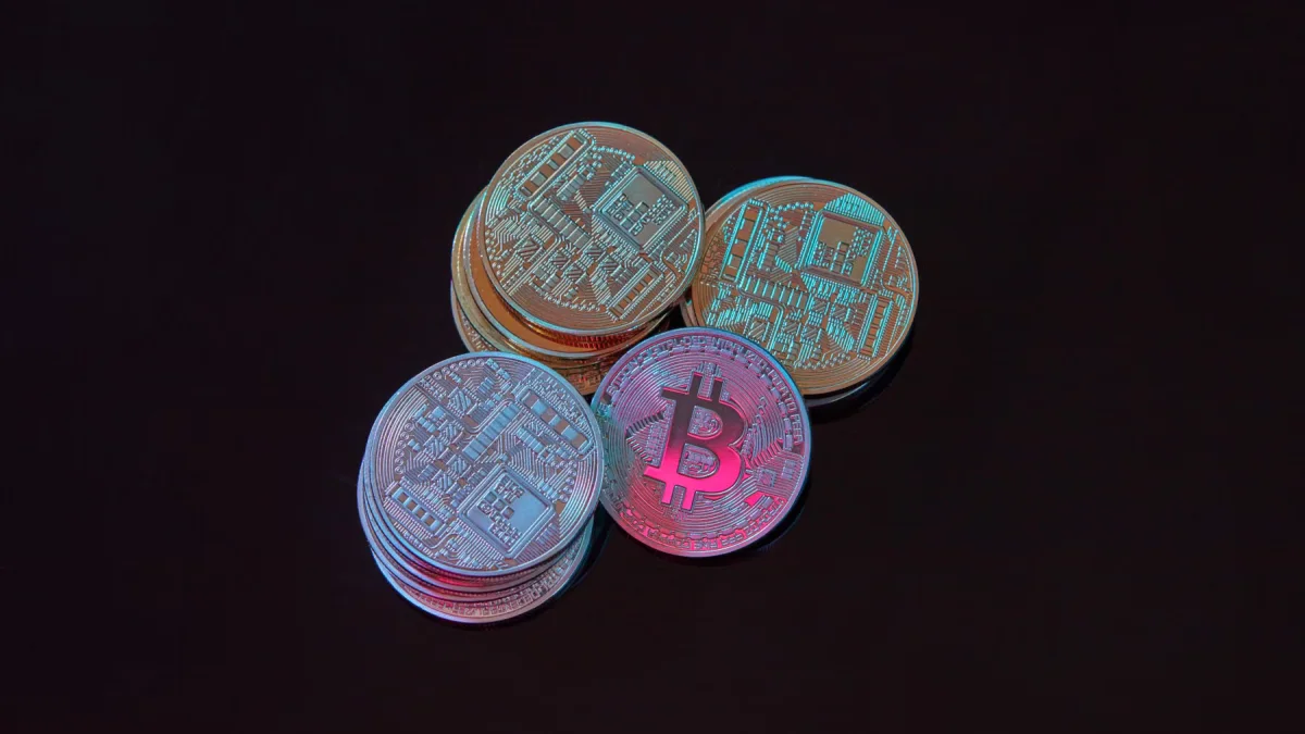 Beberapa tumpukan koin bitcoin berwarna perak dan tembaga di atas permukaan hitam