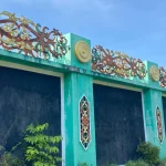 Ukiran motif Dayak berwarna terpasang di dinding beton tugu perbatasan Pancasila